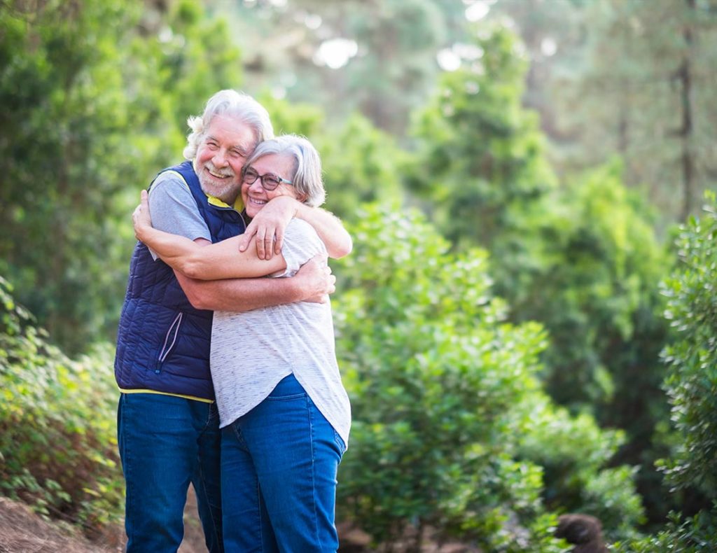senior couple hugging while on a walk in the woods annuity income loveland co